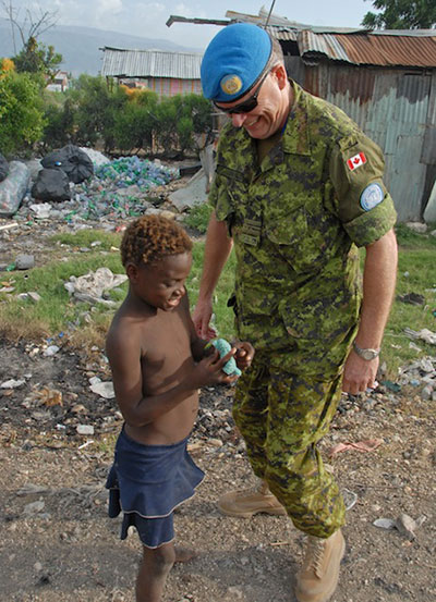 Lieutenant Commander Ian Cook, Chief of Staff coordinator for the mission MINUSTAH, speaks to a child that lives beside this main garbage depot in Port-Au-Prince. Many Haitian families live in this unsanitary environment. June 23, 2008 in Port-Au-Prince, Haiti. Photo by Sgt Robert Comeau Army News, Combat Camera.